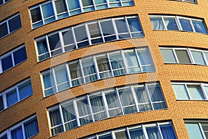 Facade of a high modern multi-storey building, a skyscraper. Background of a yellow residential tower, large glass