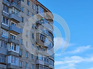 The facade of a high-rise semicircular house with balconies on a blue sky background