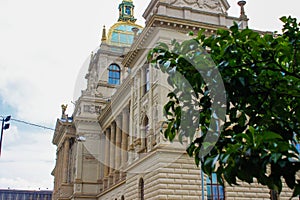 Facade of the Historical Building of the National Museum of Prague NM, NÃ¡rodnÃ­ muzeum with green leaves of a tree at the