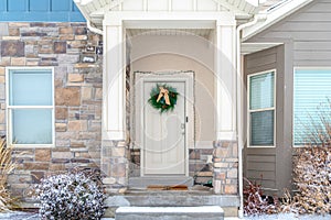 Facade of home with holiday wreath on the front door framed with string lights