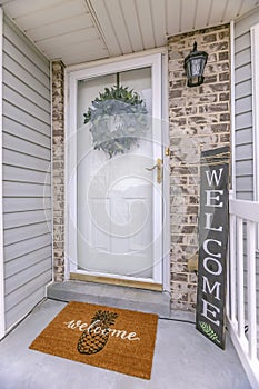 Facade of home with a leafy wreath hanging between the glass and wooden door