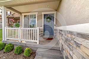 Facade of a home with railing on the porch and front door decorated with wreath