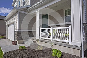 Facade of a home with view of the porch green front door and white garage door