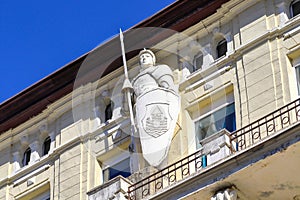 Facade of the house with a sculpture of a knight on the balcony on a sunny day