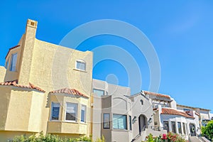 Facade of houses with painted stucco walls and clay tile roofs in San Francisco, CA