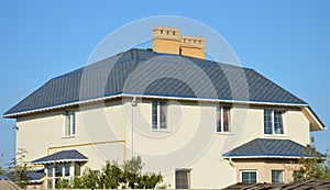 Facade of a large mansion, house with an asphalt shingled roof with a flashing around brick chimneys, roof gutters, gas pipe, air