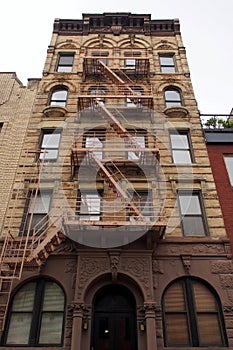 Facade of the late 19th-century multistory apartment building with old retail store in the ground floor, in the South Village, NYC