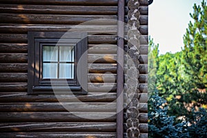 Facade of a log house with a square window.