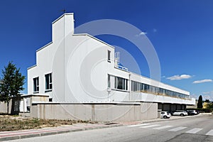 Facade of a lonely industrial building with white cladding, many windows and a clear blue sky