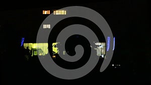 Facade with many windows, exterior of a modern apartment block at night, close up, shallow depth of the field