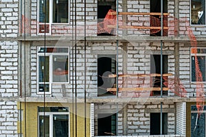 Facade of modern apartment house under construction with scaffolding