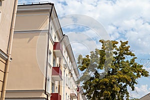 The facade of a modern building in which people live in apartments in the city center. blue sky background with tree