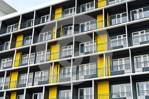 The facade of a modern multi-storey building, windows and balconies, yellow and black walls, the concept of urbanism and city