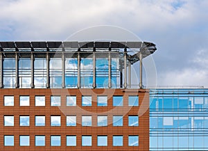 Facade of a modern office building. Square windows, attic floor and cloudy sky