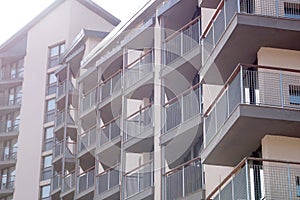 Facade of modern residential apartment building with glass balconies in sunlight