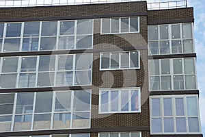 The facade of a modern residential apartment building is made of dark brown brick with panoramic windows. Architecture element