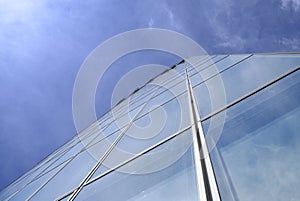Facade of modern skyscraper with reflection of cloudy sky, low angle shot, free copy space