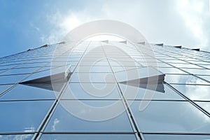 Facade of modern skyscraper with reflection of cloudy sky and sunbeams, low angle shot,copy space