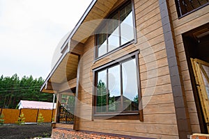 Facade of new house under construction, unfinished wooden home painted with brown natural color.