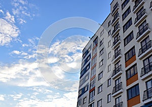 Facade of a new modern high-rise residential building. Skyscraper on blue sky background. Tall house renovation project,