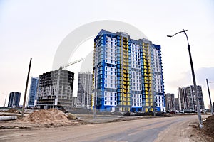 Facade of a new modern high-rise residential building. Tower crane on construction of a residential building. Cranes on formworks