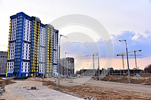 Facade of a new modern high-rise residential building. Tower crane on construction of a residential building. Cranes on formworks