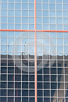 Facade of an office building with honeycomb windows and delimited in its center by a red steel cross