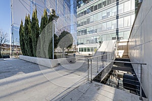 Facade of an office building with marble stairs with metal railings and decorative trees