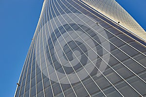 Facade of an office high-rise curved building. there are small black bulbs on the building, backlight. View from below.