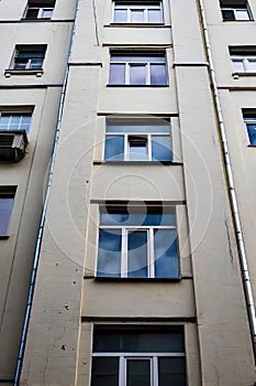 facade of old beige residential building with drainpipes