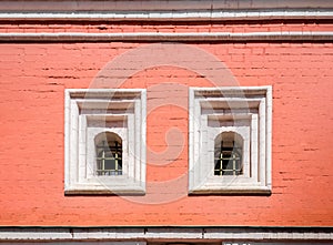 An old red brick wall with two Windows