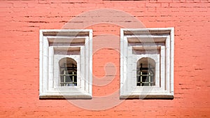 An old red brick wall with two Windows