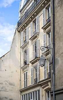 The facade of an old building with lantern and shutters on the windows