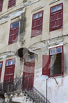 Facade of an old building with red wooden doors and windows