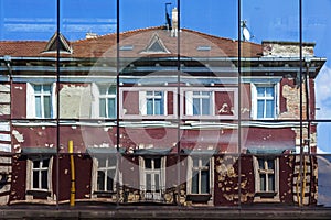 Facade of old building reflected in the windows of modern Hotel