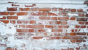 The facade of an old building. Texture of a red brick wall. Background painted with cracked white paint
