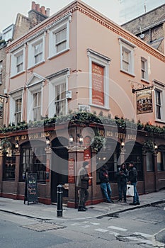 Facade of The Old Coffee House pub in Soho, London UK, people standing outside and walking past, motion blur