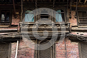 Facade of an old dusty building in Kathmandu decorated with Newari wood carving