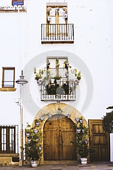 Facade of old European house with windows, balcony with flowers, wooden door in the shape of an arch