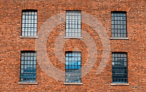 Facade of an old factory building made of red brick with a lot of vintage windows