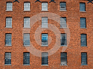 Facade  of an old factory building made of red brick with a lot of vintage windows