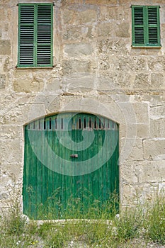 facade of an old farm. Door and windows of natural wood texture, stone walls of Mares, typical natural of Mallorca