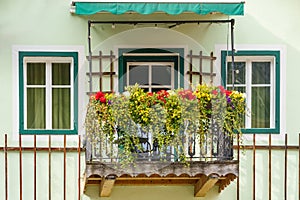 Facade of the old house in Austrian village. Balcony decorated with flowers.