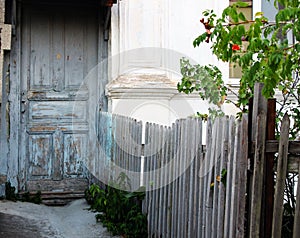 Facade of an old house with gray-blue doors and fence.