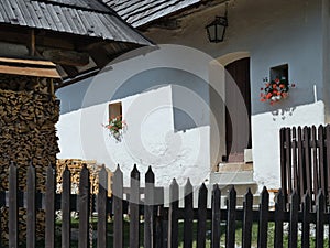 Facade of an old house with a shingle roof, wooden fence and wood prepared for winter, Vlkolinec village, Slovakia