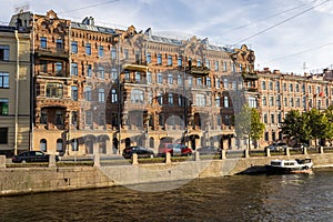 The facade of an old house in St. Petersburg. Balconies, loggias, gutters. Cars, the Fontanka River with a ship. photo