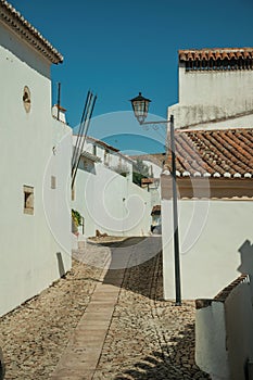 Facade of old houses with whitewashed wall in alley on slope