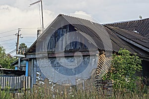 Facade of an old rural house with a blue wooden attic