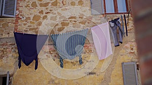 Facade of old stone house with washed colored clothes drying on rope outside
