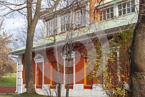 Facade of an old two-story red brick building with a white roof in the autumn park